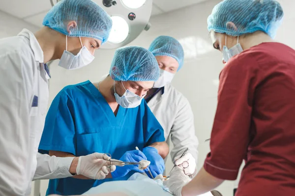 Grupo de cirurgiões a trabalhar no teatro cirúrgico. Equipa de medicina de ressuscitação usando máscaras protetoras — Fotografia de Stock