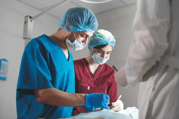 Grupo de cirurgiões a trabalhar no teatro cirúrgico. Equipa de medicina de ressuscitação usando máscaras protetoras — Fotografia de Stock