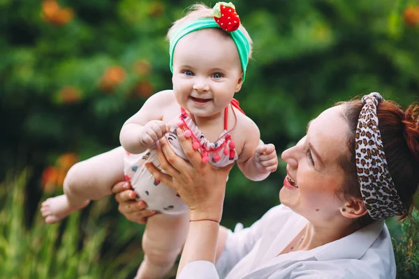 Happy harmonious family outdoors. mother throws baby up, laughing and playing in the summer on the nature. — Stock Photo, Image