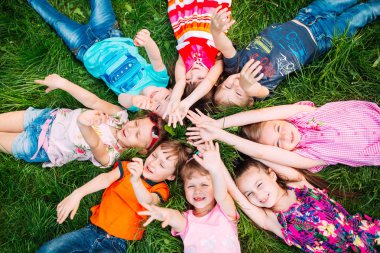 Parktaki yeşil çimlerin üzerinde yatan bir grup çocuk. Çocukların etkileşimi....