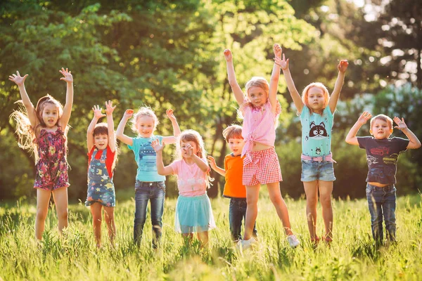 Group of friends running happily together in the grass and jumping. — Stock Photo, Image