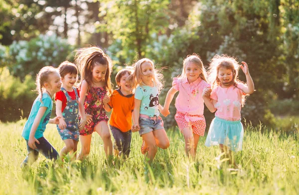 Eine große Gruppe von Kindern, befreundeten Jungen und Mädchen läuft an einem sonnigen Sommertag in Freizeitkleidung durch den Park . — Stockfoto