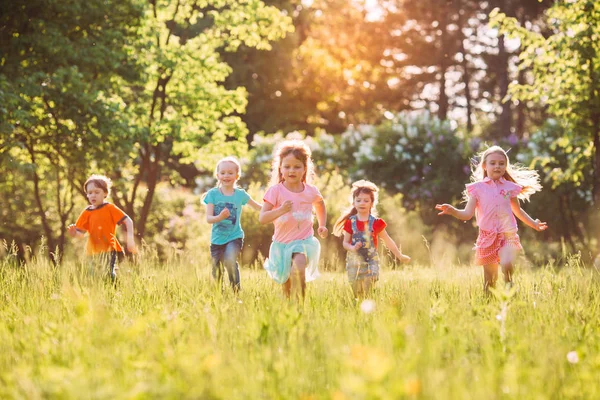 Gran grupo de niños, amigos, niños y niñas corriendo en el parque en el soleado día de verano con ropa casual . —  Fotos de Stock