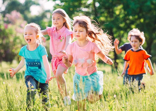 Eine große Gruppe von Kindern, befreundeten Jungen und Mädchen läuft an einem sonnigen Sommertag in Freizeitkleidung durch den Park . — Stockfoto