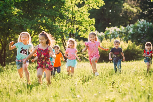 Eine große Gruppe von Kindern, befreundeten Jungen und Mädchen läuft an einem sonnigen Sommertag in Freizeitkleidung durch den Park . — Stockfoto