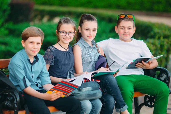 Buon Ritratto dei compagni di scuola. Compagni di scuola seduti con libri in una panchina di legno in un parco cittadino e che studiano nelle giornate di sole. — Foto Stock