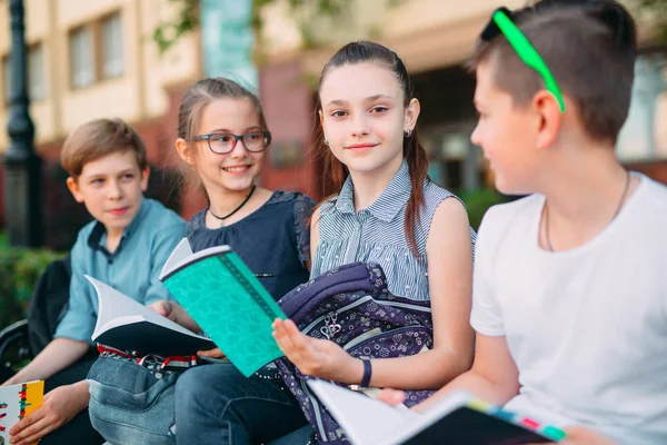 Buon Ritratto dei compagni di scuola. Compagni di scuola seduti con libri in una panchina di legno in un parco cittadino e che studiano nelle giornate di sole. — Foto Stock