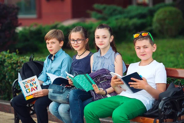 Happy Schoolmates Portrait. camarades de classe assis avec des livres dans un banc en bois dans un parc de la ville et étudier par une journée ensoleillée. — Photo