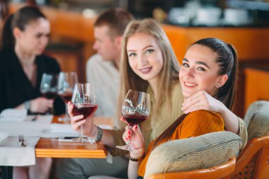 Arkadaşlar şarap içerek, konuşarak ve gülümseyerek eğlenirler..