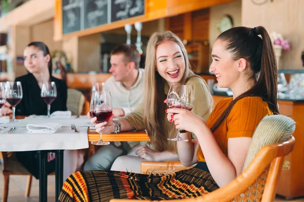 Gli amici si divertono a bere vino, parlare e sorridere al ristorante. — Foto Stock