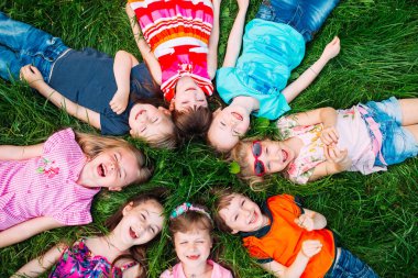 Parktaki yeşil çimlerin üzerinde yatan bir grup çocuk. Çocukların etkileşimi....
