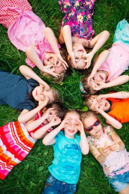 Parktaki yeşil çimlerin üzerinde yatan bir grup çocuk. Çocukların etkileşimi....