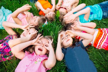 Parktaki yeşil çimlerin üzerinde yatan bir grup çocuk. Çocukların etkileşimi....