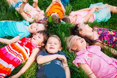Parktaki yeşil çimlerin üzerinde yatan bir grup çocuk. Çocukların etkileşimi....