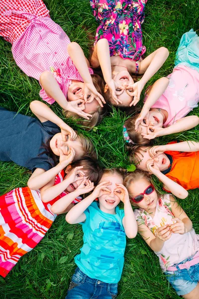 Μια ομάδα παιδιών που κείτονται στο πράσινο γρασίδι στο πάρκο. Η αλληλεπίδραση των παιδιών. — Φωτογραφία Αρχείου