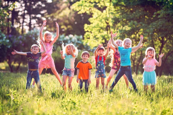 Freundeskreis rennt fröhlich zusammen im Gras und springt. — Stockfoto