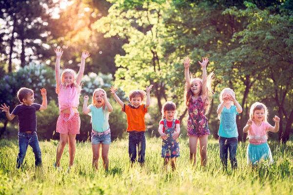 Grupo de amigos corriendo felices juntos en la hierba y saltando. —  Fotos de Stock