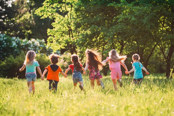 Grande gruppo di bambini, amici ragazzi e ragazze che corrono nel parco nella soleggiata giornata estiva in abiti casual . — Foto Stock