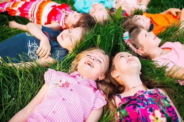 Un groupe d'enfants couchés sur l'herbe verte dans le parc. L'interaction des enfants. — Photo