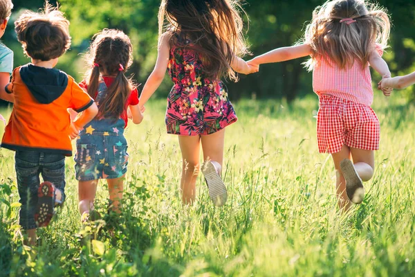 Eine große Gruppe von Kindern, befreundeten Jungen und Mädchen läuft an einem sonnigen Sommertag in Freizeitkleidung durch den Park . — Stockfoto