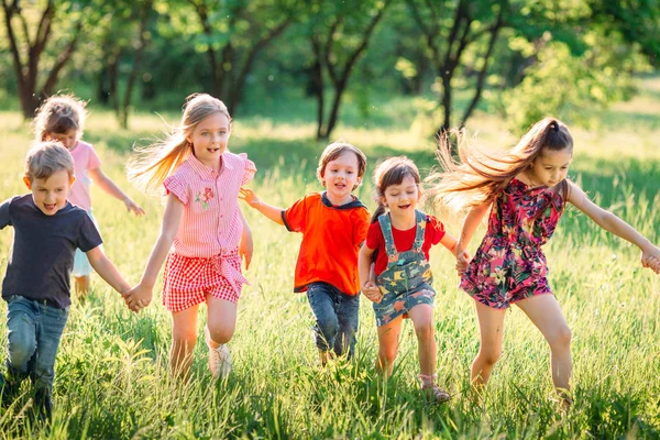 Büyük bir grup çocuk, arkadaşlar güneşli bir yaz gününde parkta günlük kıyafetlerle koşuşturuyorlar. . — Stok fotoğraf