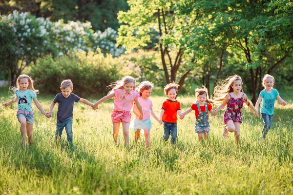 Large group of kids, friends boys and girls running in the park on sunny summer day in casual clothes . — Stock Photo, Image