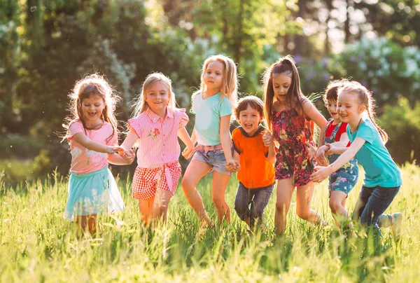 Eine große Gruppe von Kindern, befreundeten Jungen und Mädchen läuft an einem sonnigen Sommertag in Freizeitkleidung durch den Park . — Stockfoto