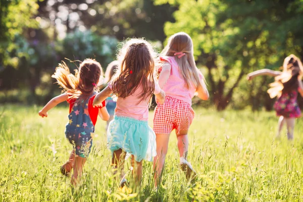 Eine große Gruppe von Kindern, befreundeten Jungen und Mädchen läuft an einem sonnigen Sommertag in Freizeitkleidung durch den Park . — Stockfoto