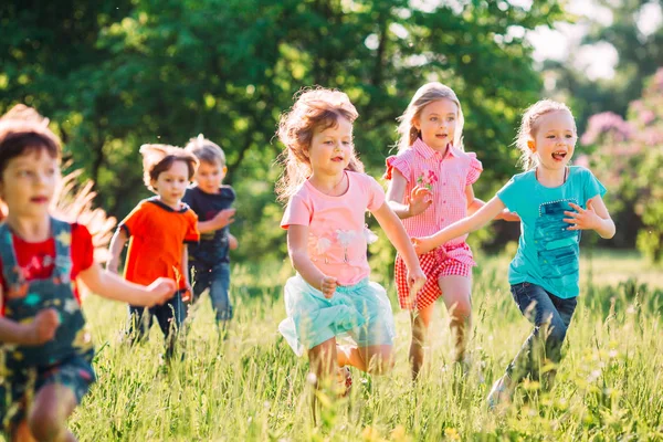 Grande gruppo di bambini, amici ragazzi e ragazze che corrono nel parco nella soleggiata giornata estiva in abiti casual . — Foto Stock