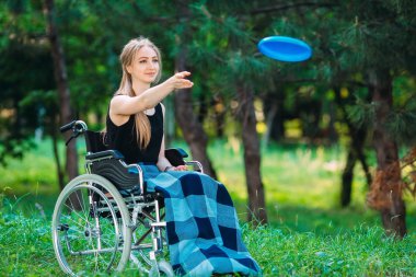 Genç engelli bir kız küçük kız kardeşiyle frizbi oynuyor. Sağlıklı bir insanın engelli biriyle etkileşimi
