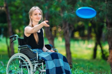 Genç engelli bir kız küçük kız kardeşiyle frizbi oynuyor. Sağlıklı bir insanın engelli biriyle etkileşimi