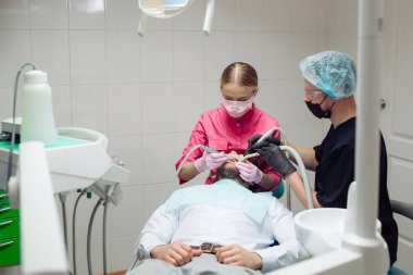 Profesyonel diş temizliği. Dişçi, erkek bir hastanın dişlerini temizler..