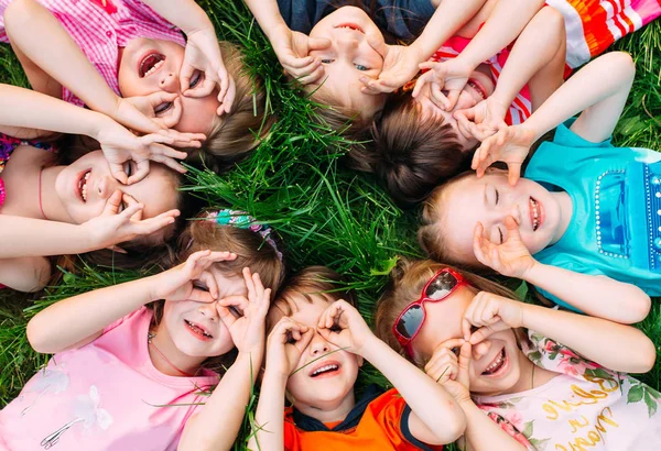 A group of children lying on the green grass in the Park. The interaction of the children. — Stock Photo, Image
