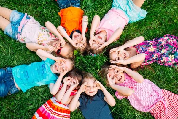 Група дітей лежить на зеленій траві в парку. Взаємодія дітей . — стокове фото