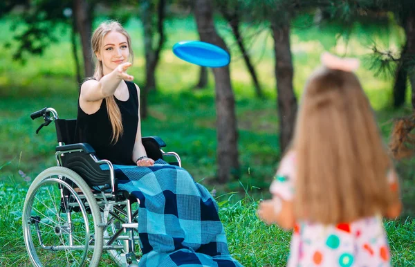Genç engelli bir kız küçük kız kardeşiyle frizbi oynuyor. Sağlıklı bir insanın engelli biriyle etkileşimi