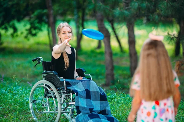 Une jeune fille handicapée joue au frisbee avec sa sœur cadette. Interaction d'une personne en bonne santé avec une personne handicapée — Photo