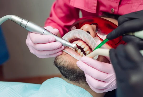 Professional teeth cleaning. Dentist cleans the teeth of a male patient. — Stock Photo, Image