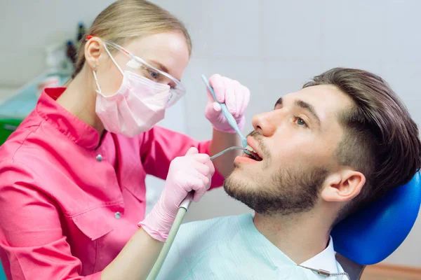 Professional teeth cleaning. Dentist cleans the teeth of a male patient.