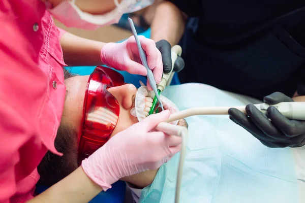 Επαγγελματικός καθαρισμός δοντιών. Οδοντίατρος καθαρίζει τα δόντια ενός άνδρα ασθενή. — Φωτογραφία Αρχείου