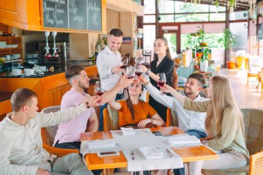 Arkadaşlar restoranın terasında şarap içerler..