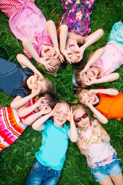 Parktaki yeşil çimlerin üzerinde yatan bir grup çocuk. Çocukların etkileşimi....