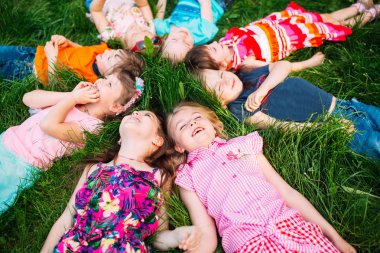 Parktaki yeşil çimlerin üzerinde yatan bir grup çocuk. Çocukların etkileşimi....