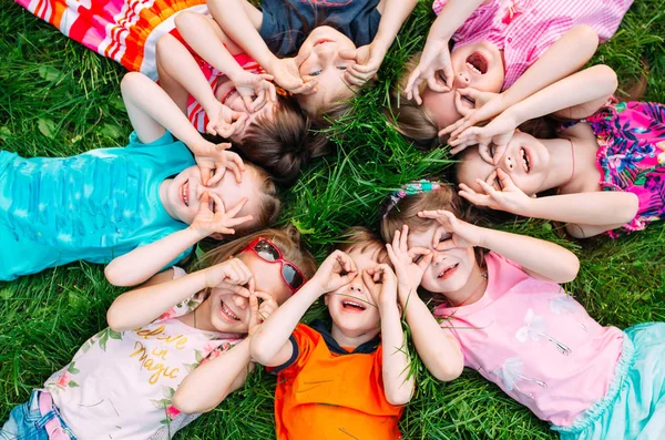 공원에 있는 푸른 잔디 위에 누워 있는 아이들의 무리입니다. 자녀들의 상호 작용. — 스톡 사진