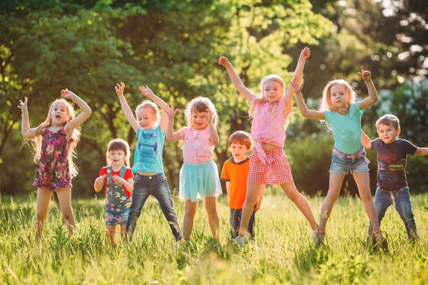 Grupo de amigos corriendo felices juntos en la hierba y saltando. —  Fotos de Stock