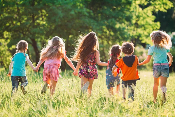 Eine große Gruppe von Kindern, befreundeten Jungen und Mädchen läuft an einem sonnigen Sommertag in Freizeitkleidung durch den Park . — Stockfoto