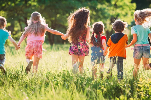 Велика група дітей, друзів хлопчиків і дівчаток, що біжать в парку в сонячний літній день в повсякденному одязі  . — стокове фото