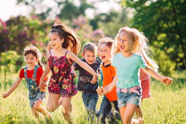 Eine große Gruppe von Kindern, befreundeten Jungen und Mädchen läuft an einem sonnigen Sommertag in Freizeitkleidung durch den Park . — Stockfoto