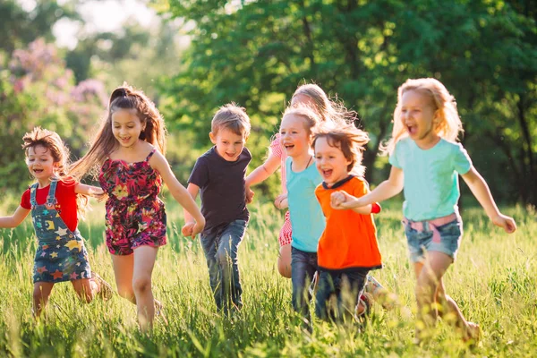 Grand groupe d'enfants, d'amis garçons et de filles courant dans le parc le jour ensoleillé de l'été en vêtements décontractés . — Photo