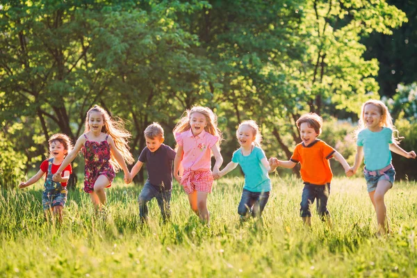 Grand groupe d'enfants, d'amis garçons et de filles courant dans le parc le jour ensoleillé de l'été en vêtements décontractés . — Photo