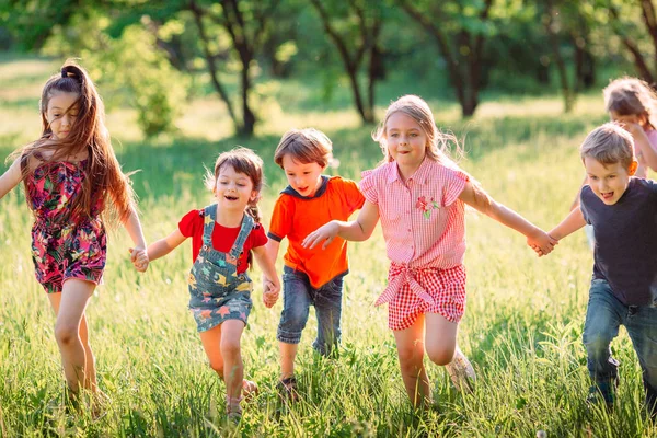 Μεγάλη ομάδα παιδιών, φίλων αγόρια και κορίτσια που τρέχουν στο πάρκο την ηλιόλουστη καλοκαιρινή μέρα με casual ρούχα . — Φωτογραφία Αρχείου